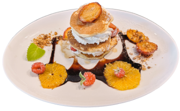 Amerykańskie pancake z bitą śmietaną, owocami i syropem klonowym